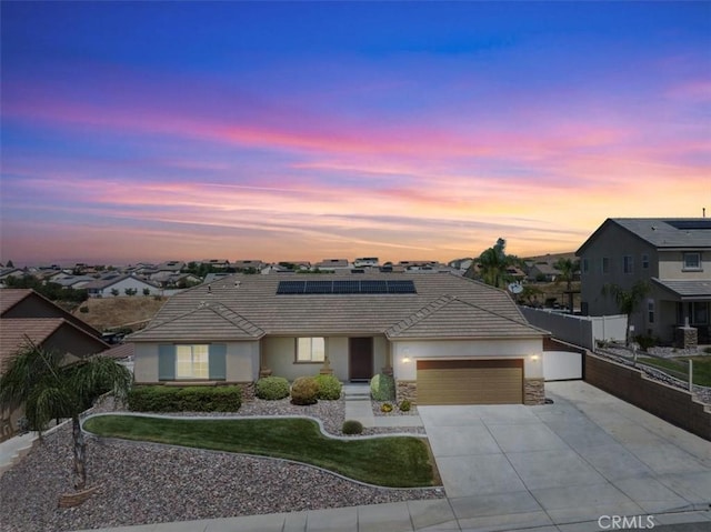 1472 Coyote Ln, Calimesa, CA 92320 - single story home featuring a garage, concrete driveway, roof mounted solar panels, stucco siding, and a residential view