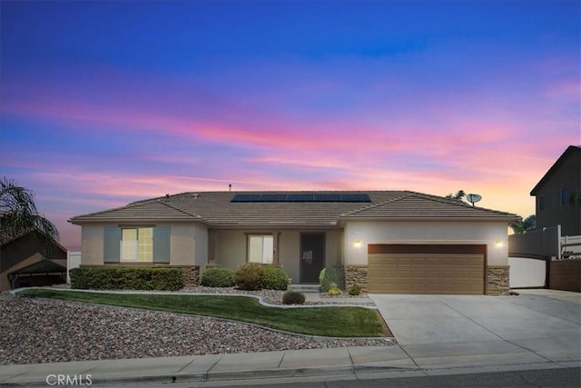 1472 Coyote Ln, Calimesa, CA 92320 - ranch-style home with stucco siding, an attached garage, driveway, stone siding, and solar panels