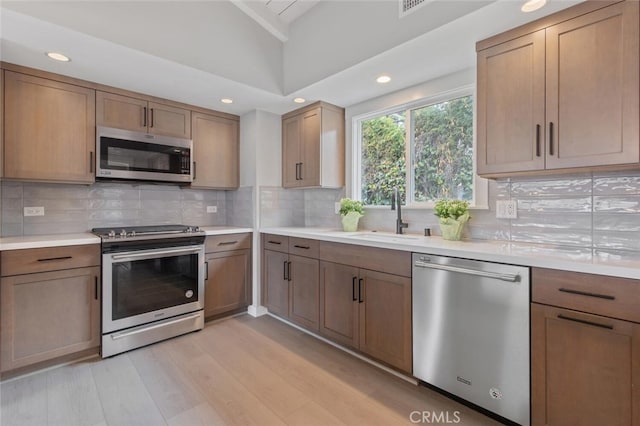 50 Quinta Vista Dr, Thousand Oaks, CA 91362 - kitchen featuring stainless steel appliances, a sink, vaulted ceiling, light countertops, and light wood finished floors