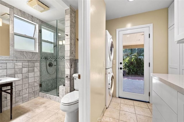 15454 Sutton St, Sherman Oaks, CA 91403 - bathroom featuring stacked washer / dryer, vanity, tile patterned floors, toilet, and a stall shower