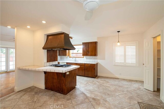 10425 Hillview Ave, Chatsworth, CA 91311 - kitchen with custom exhaust hood, tile countertops, decorative backsplash, a ceiling fan, and stainless steel gas stovetop