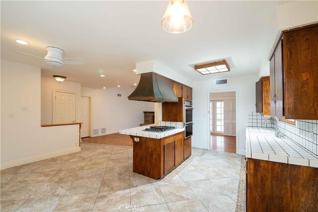 10425 Hillview Ave, Chatsworth, CA 91311 - kitchen featuring tile counters, wall chimney exhaust hood, appliances with stainless steel finishes, backsplash, and ceiling fan