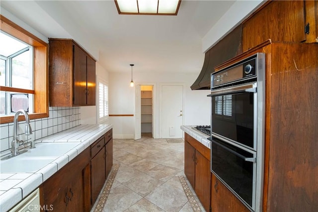 10425 Hillview Ave, Chatsworth, CA 91311 - kitchen with tile countertops, a sink, tasteful backsplash, decorative light fixtures, and baseboards