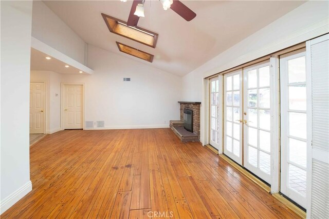 10425 Hillview Ave, Chatsworth, CA 91311 - unfurnished living room featuring vaulted ceiling, a ceiling fan, light wood-style floors, a stone fireplace, and a skylight