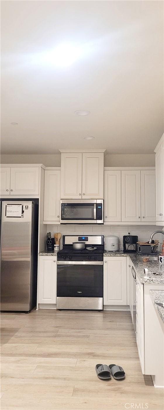 163 Lantana Dr, Stanton, CA 90680 - kitchen with appliances with stainless steel finishes, white cabinets, a sink, light stone countertops, and light wood-style floors