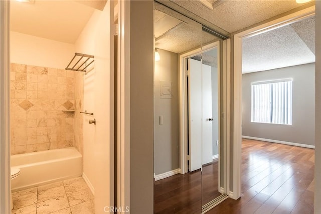 1422 Rock Glen Ave Unit 210, Glendale, CA 91205 - bathroom with baseboards, toilet, washtub / shower combination, and a textured ceiling
