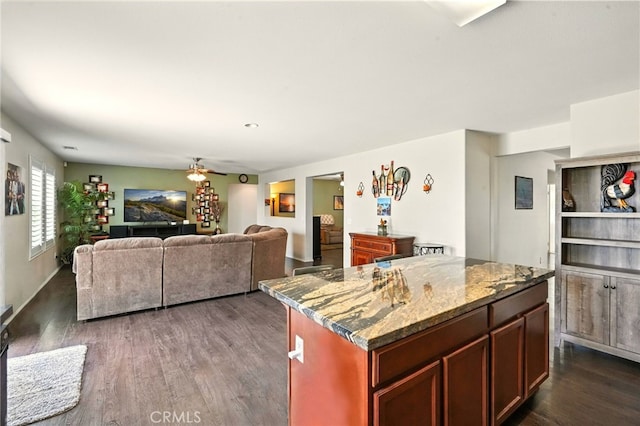 6875 Adainville Dr, Palmdale, CA 93552 - kitchen with dark wood-type flooring, a ceiling fan, stone counters, open floor plan, and a center island