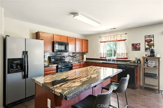 6875 Adainville Dr, Palmdale, CA 93552 - kitchen with black appliances, a breakfast bar, dark wood-style floors, and a kitchen island