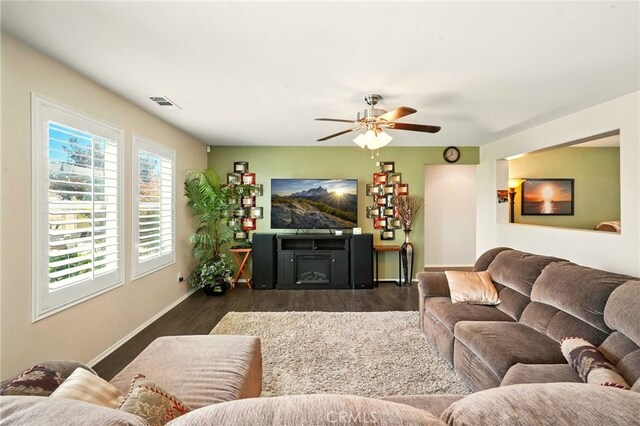 6875 Adainville Dr, Palmdale, CA 93552 - living room with dark wood-style floors, ceiling fan, and a fireplace