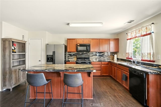 6875 Adainville Dr, Palmdale, CA 93552 - kitchen with black appliances, dark wood-style flooring, a center island, a breakfast bar, and tasteful backsplash