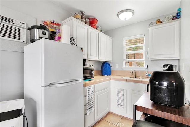 22428 Valley View Rd, Apple Valley, CA 92308 - kitchen with freestanding refrigerator, a sink, tile counters, and white cabinetry