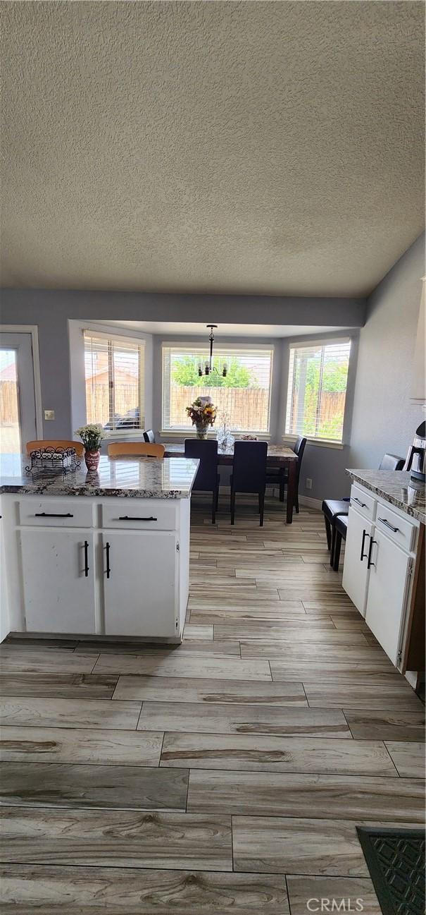 15009 Hopland St, Victorville, CA 92394 - kitchen with white cabinets, light wood-type flooring, a textured ceiling, and light stone countertops