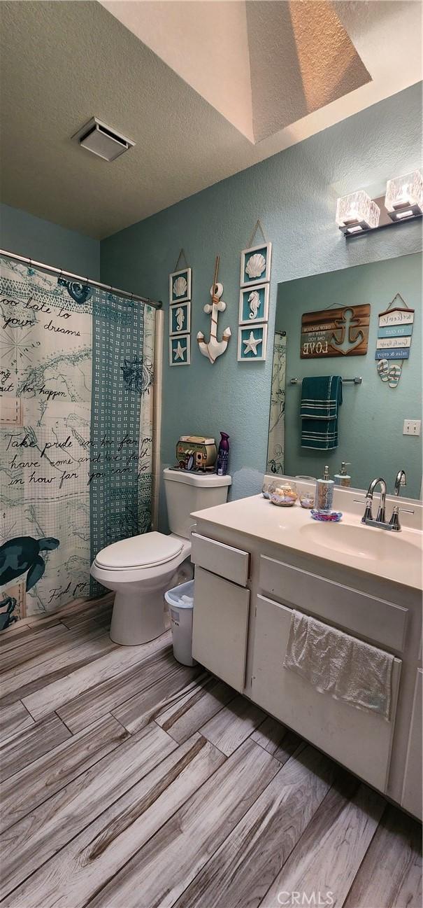 15009 Hopland St, Victorville, CA 92394 - bathroom with toilet, wood finished floors, vanity, and a textured ceiling