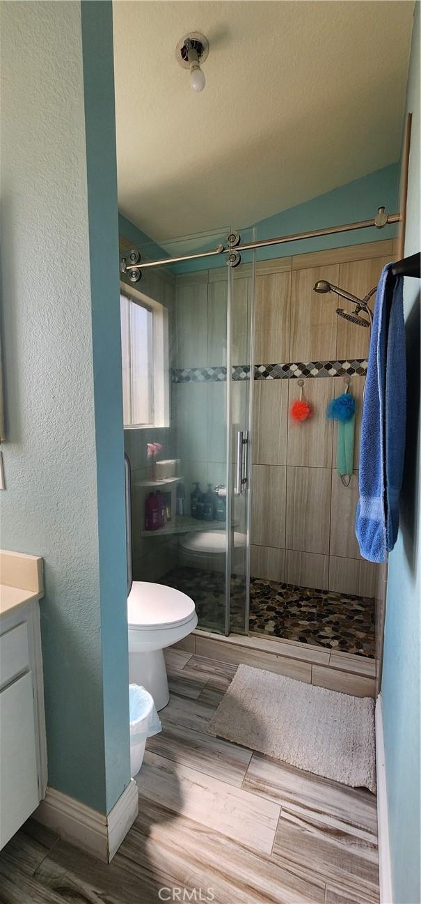 15009 Hopland St, Victorville, CA 92394 - bathroom featuring toilet, a stall shower, vanity, wood finished floors, and baseboards