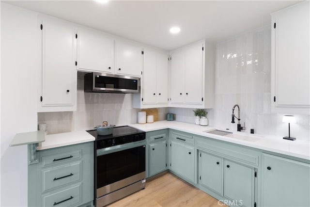 3695 Linden Ave Unit 10C, Long Beach, CA 90807 - kitchen featuring a sink, appliances with stainless steel finishes, decorative backsplash, white cabinetry, and recessed lighting
