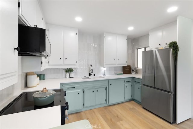 3695 Linden Ave Unit 10C, Long Beach, CA 90807 - kitchen with freestanding refrigerator, a sink, light countertops, white cabinetry, and light wood finished floors