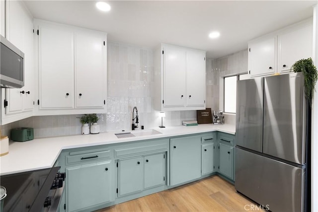 3695 Linden Ave Unit 10C, Long Beach, CA 90807 - kitchen featuring stainless steel appliances, a sink, white cabinets, light wood finished floors, and backsplash