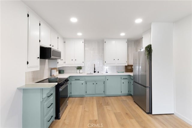3695 Linden Ave Unit 10C, Long Beach, CA 90807 - kitchen featuring black electric range oven, freestanding refrigerator, a sink, light wood-style floors, and backsplash