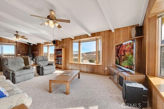 28560 Cruthers Creek Rd, Pearblossom, CA 93553 - living room featuring a wood stove, ceiling fan, wood walls, and light colored carpet