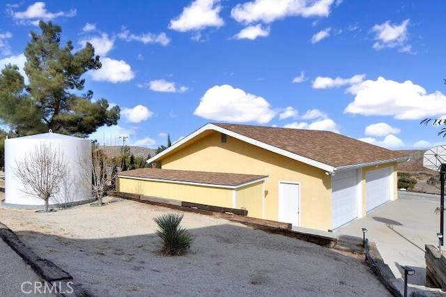 28560 Cruthers Creek Rd, Pearblossom, CA 93553 - view of front of house featuring a detached garage, stucco siding, and roof with shingles