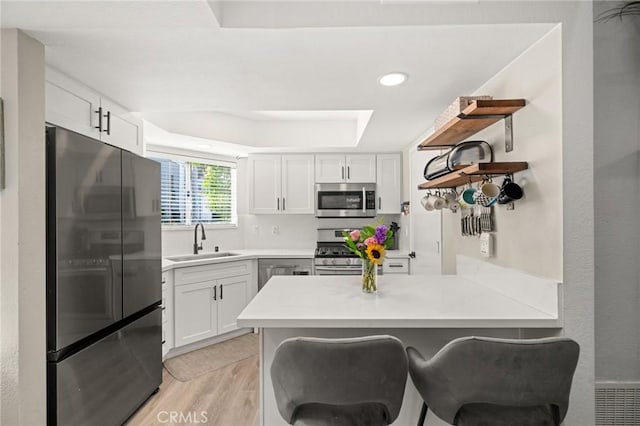 511 San Nicholas Ct, Laguna Beach, CA 92651 - kitchen with appliances with stainless steel finishes, a peninsula, light wood-style floors, open shelves, and white cabinets