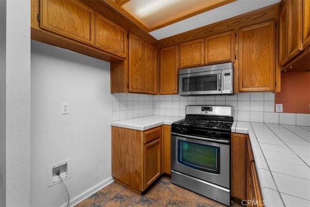 22022 Grove Cir, Red Bluff, CA 96080 - kitchen with stainless steel appliances, tile counters, brown cabinets, backsplash, and baseboards