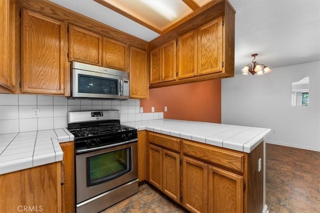 22022 Grove Cir, Red Bluff, CA 96080 - kitchen featuring appliances with stainless steel finishes, a peninsula, decorative backsplash, and brown cabinets