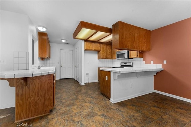 22022 Grove Cir, Red Bluff, CA 96080 - kitchen with stainless steel microwave, tile countertops, a peninsula, and range