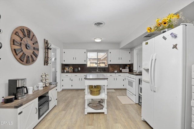 10217 Enger St, Bakersfield, CA 93312 - kitchen with white appliances, dark countertops, light wood-style flooring, a sink, and white cabinetry
