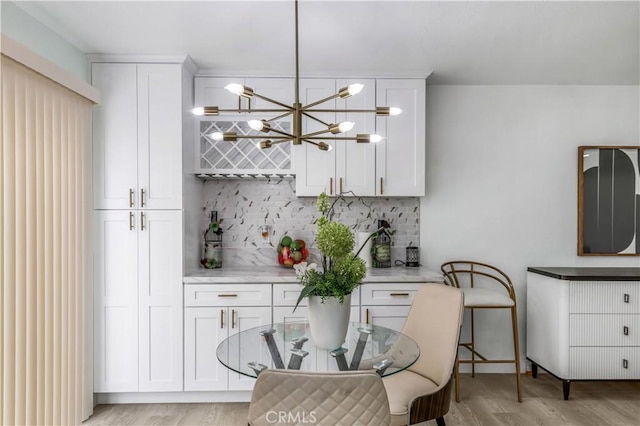 10415 Mapledale St, Bellflower, CA 90706 - kitchen featuring decorative backsplash, white cabinetry, light countertops, and light wood finished floors