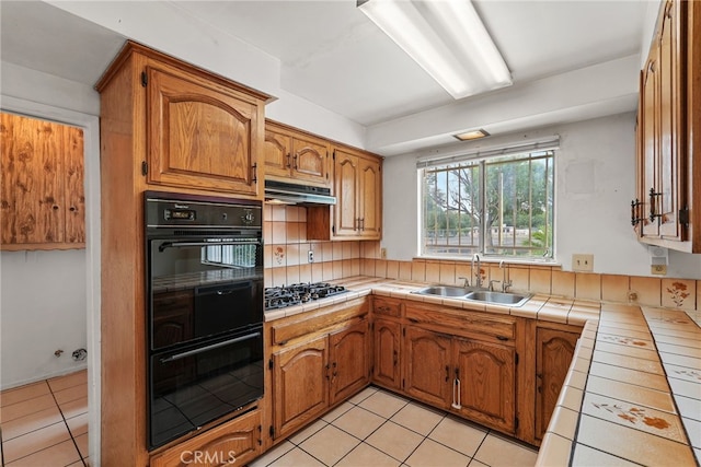 10120 Andasol Ave, Northridge, CA 91325 - kitchen with a sink, tile countertops, under cabinet range hood, black appliances, and light tile patterned floors
