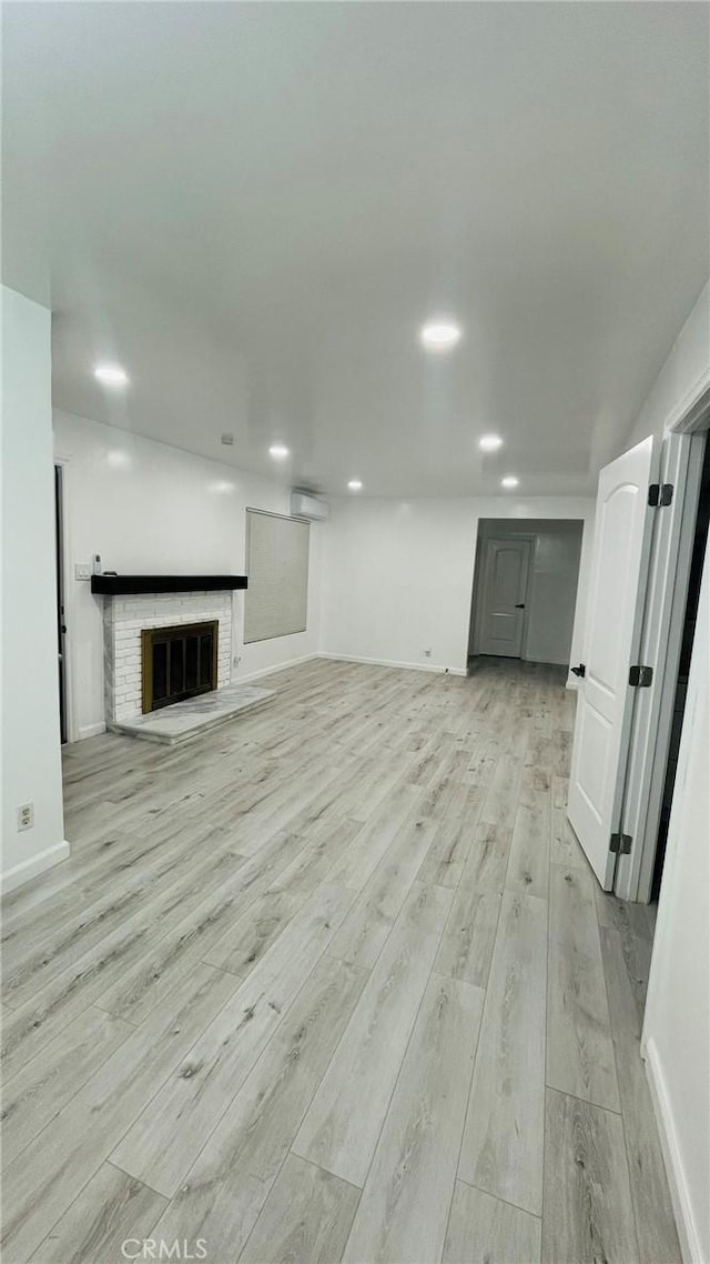 14940 Beckner St, La Puente, CA 91744 - unfurnished living room with light wood finished floors, baseboards, a fireplace, and an AC wall unit