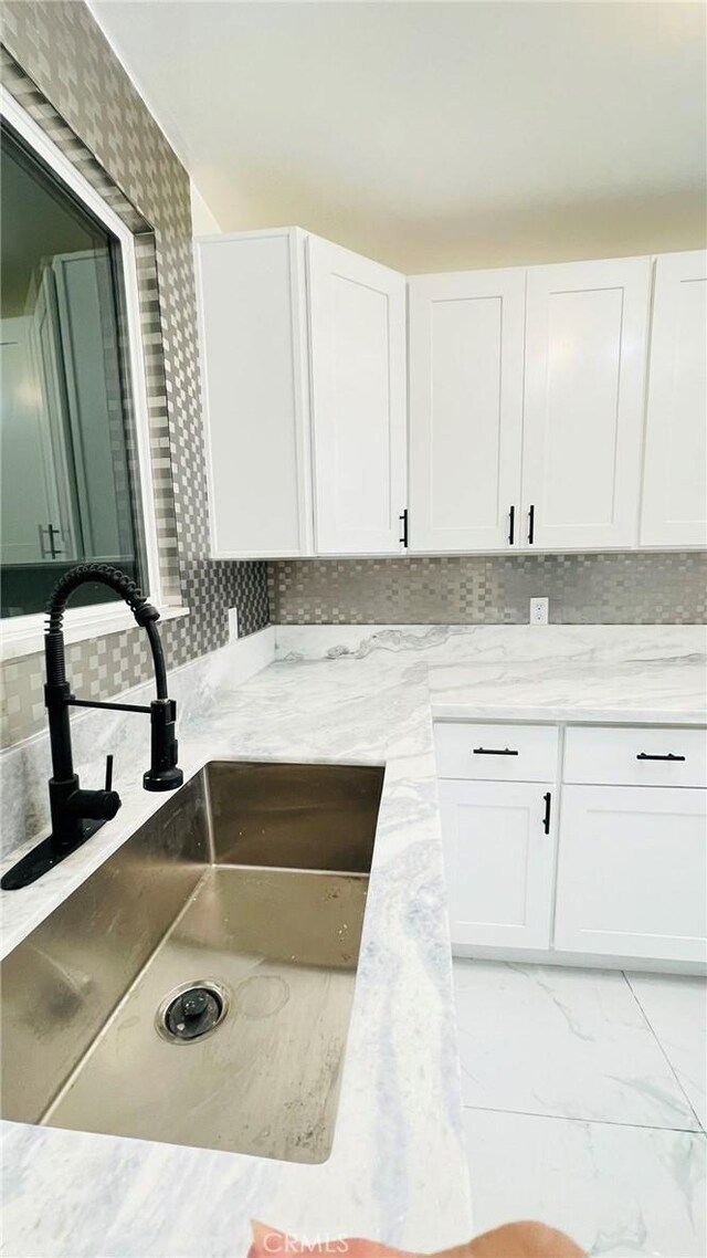 14940 Beckner St, La Puente, CA 91744 - kitchen view of a sink, white cabinetry, tasteful backsplash, and light stone counters