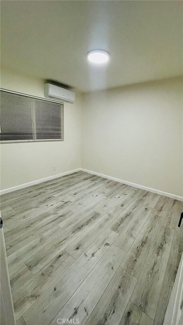 14940 Beckner St, La Puente, CA 91744 - empty room with a wall mounted AC, wood finished floors, and baseboards