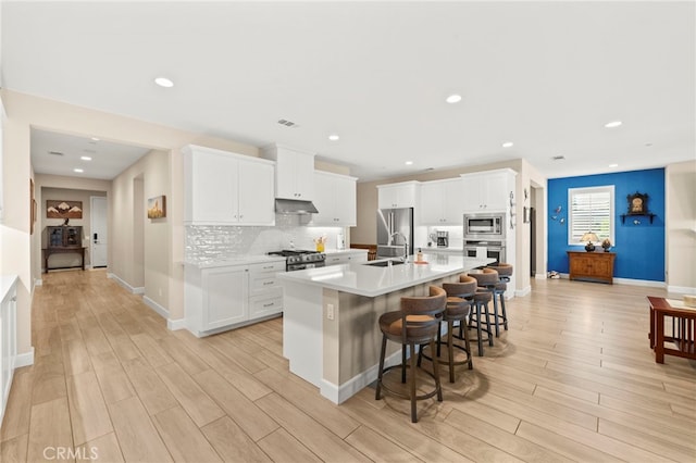 34452 Turquoise Ln, Murrieta, CA 92563 - kitchen with appliances with stainless steel finishes, a sink, light wood-type flooring, a breakfast bar, and recessed lighting