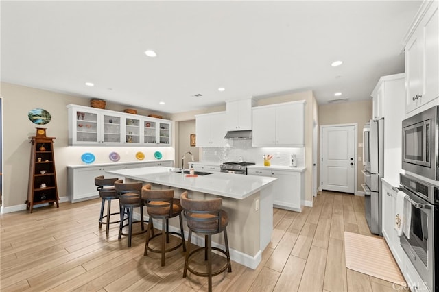 34452 Turquoise Ln, Murrieta, CA 92563 - kitchen with under cabinet range hood, a sink, high quality appliances, a breakfast bar area, and an island with sink