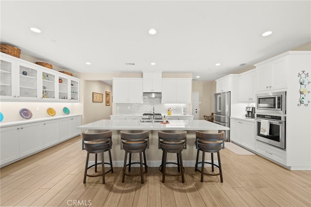 34452 Turquoise Ln, Murrieta, CA 92563 - kitchen featuring stainless steel appliances, under cabinet range hood, a breakfast bar area, an island with sink, and recessed lighting