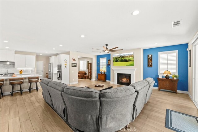 34452 Turquoise Ln, Murrieta, CA 92563 - living area featuring a glass covered fireplace, light wood-style floors, ceiling fan, recessed lighting, and baseboards