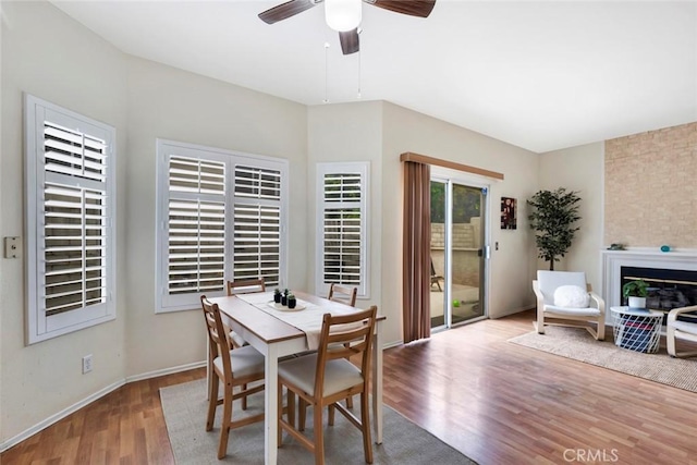 13421 Hubbard St Unit 125, Sylmar, CA 91342 - dining space with wood finished floors, a glass covered fireplace, a ceiling fan, and baseboards