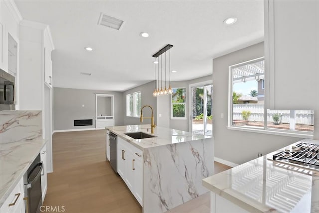 9406 Glenaire Ct, Rancho Cucamonga, CA 91730 - kitchen with a sink, appliances with stainless steel finishes, white cabinetry, light wood-style flooring, and an island with sink