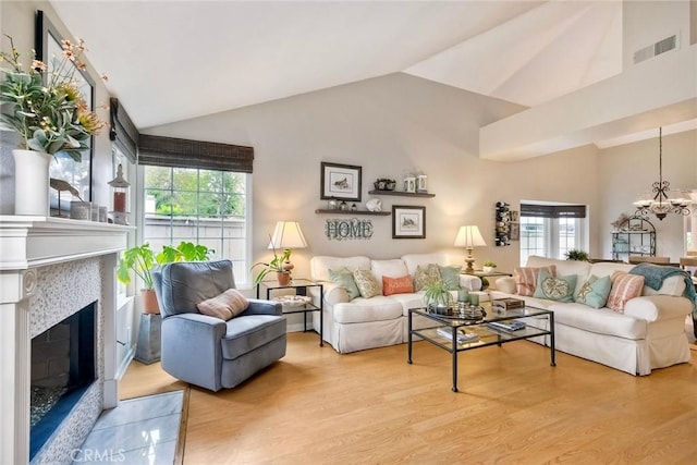 543 Rockport Ct, Encinitas, CA 92024 - living room featuring a chandelier, lofted ceiling, light wood-style flooring, and a glass covered fireplace