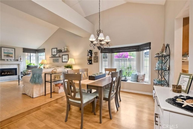 543 Rockport Ct, Encinitas, CA 92024 - dining space featuring light wood-style flooring, a chandelier, a glass covered fireplace, high vaulted ceiling, and baseboards