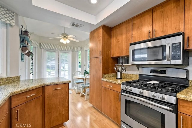 543 Rockport Ct, Encinitas, CA 92024 - kitchen with stainless steel appliances, a tray ceiling, brown cabinetry, and light wood-style floors