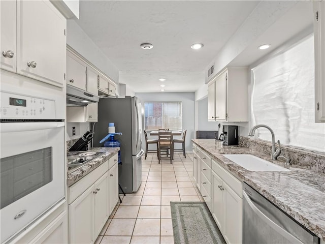 7352 N Adoline Ave, Fresno, CA 93711 - kitchen featuring appliances with stainless steel finishes, a sink, under cabinet range hood, light tile patterned flooring, and white cabinetry
