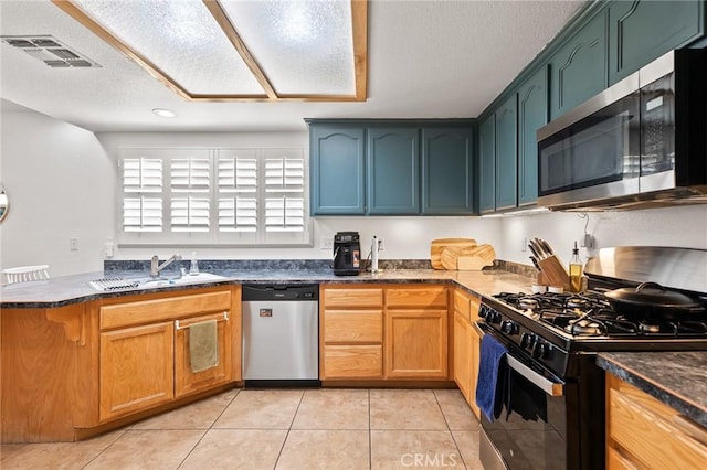 57146 Selecta Ave, Yucca Valley, CA 92284 - kitchen with stainless steel appliances, a sink, light tile patterned flooring, a textured ceiling, and a peninsula