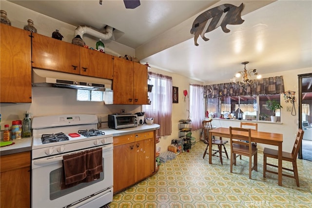 6532 Bonnie Vale Ave, Pico Rivera, CA 90660 - kitchen with white gas range, under cabinet range hood, a chandelier, brown cabinetry, and light countertops
