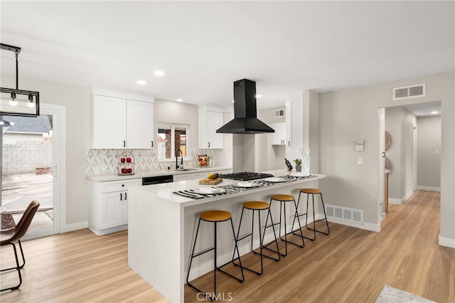 1905 Davis St, Corona, CA 92882 - kitchen with island range hood, a kitchen breakfast bar, light wood-style flooring, white cabinets, and recessed lighting