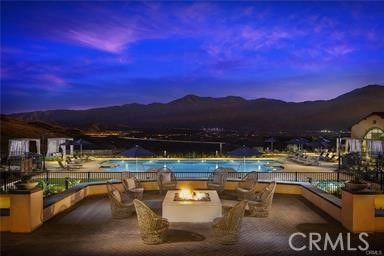 24385 Overlook Dr, Corona, CA 92883 - pool at dusk featuring a fire pit, a mountain view, a patio area, and a community pool