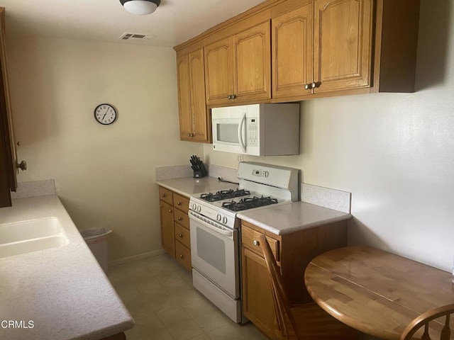 312 Rhodes Ct, Fillmore, CA 93015 - kitchen with white appliances, light countertops, brown cabinetry, and light tile patterned floors