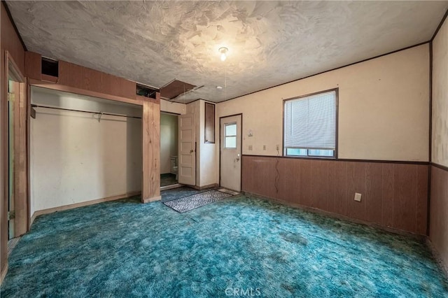 14410 Walnut Ave, Clearlake, CA 95422 - unfurnished bedroom featuring wooden walls, a wainscoted wall, carpet floors, a textured ceiling, and a closet